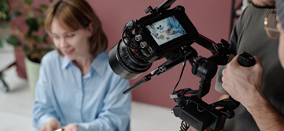 Primer plano de cámara filmando demostración de producto con ejecutiva en oficina.